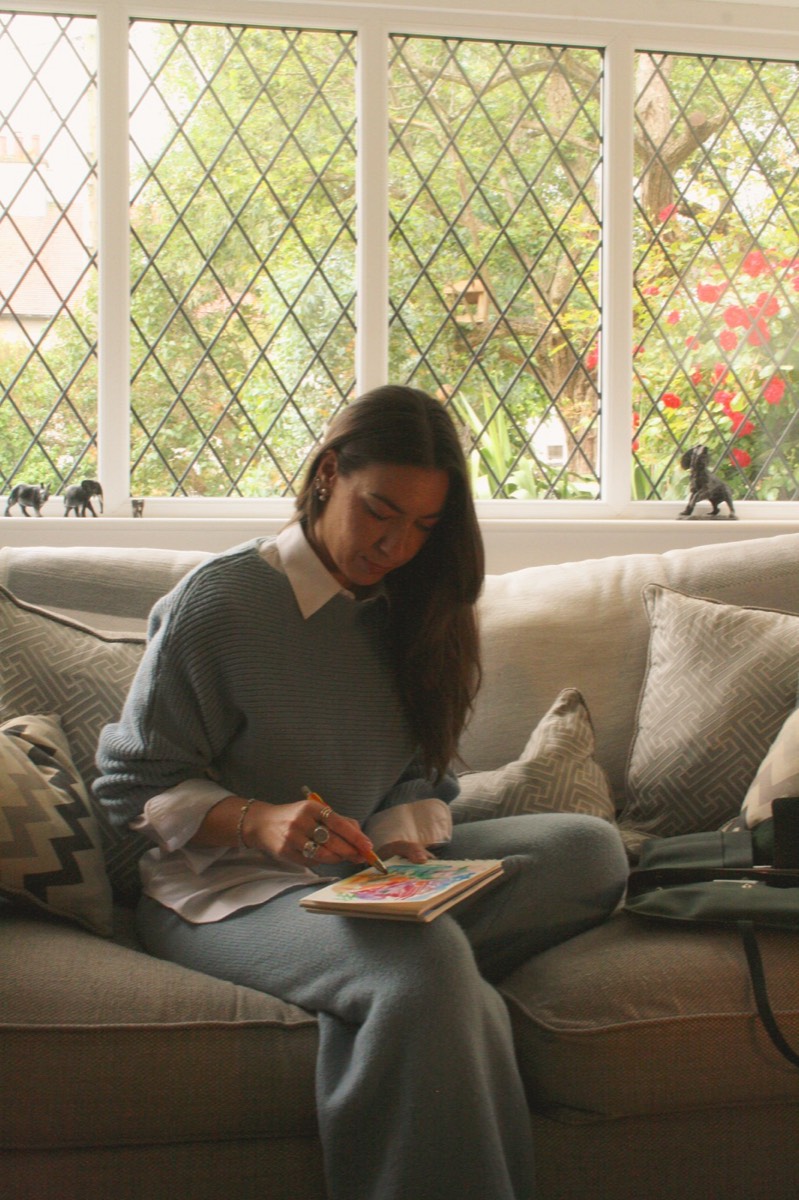 Lou Lou sketching in a notebook on a sofa