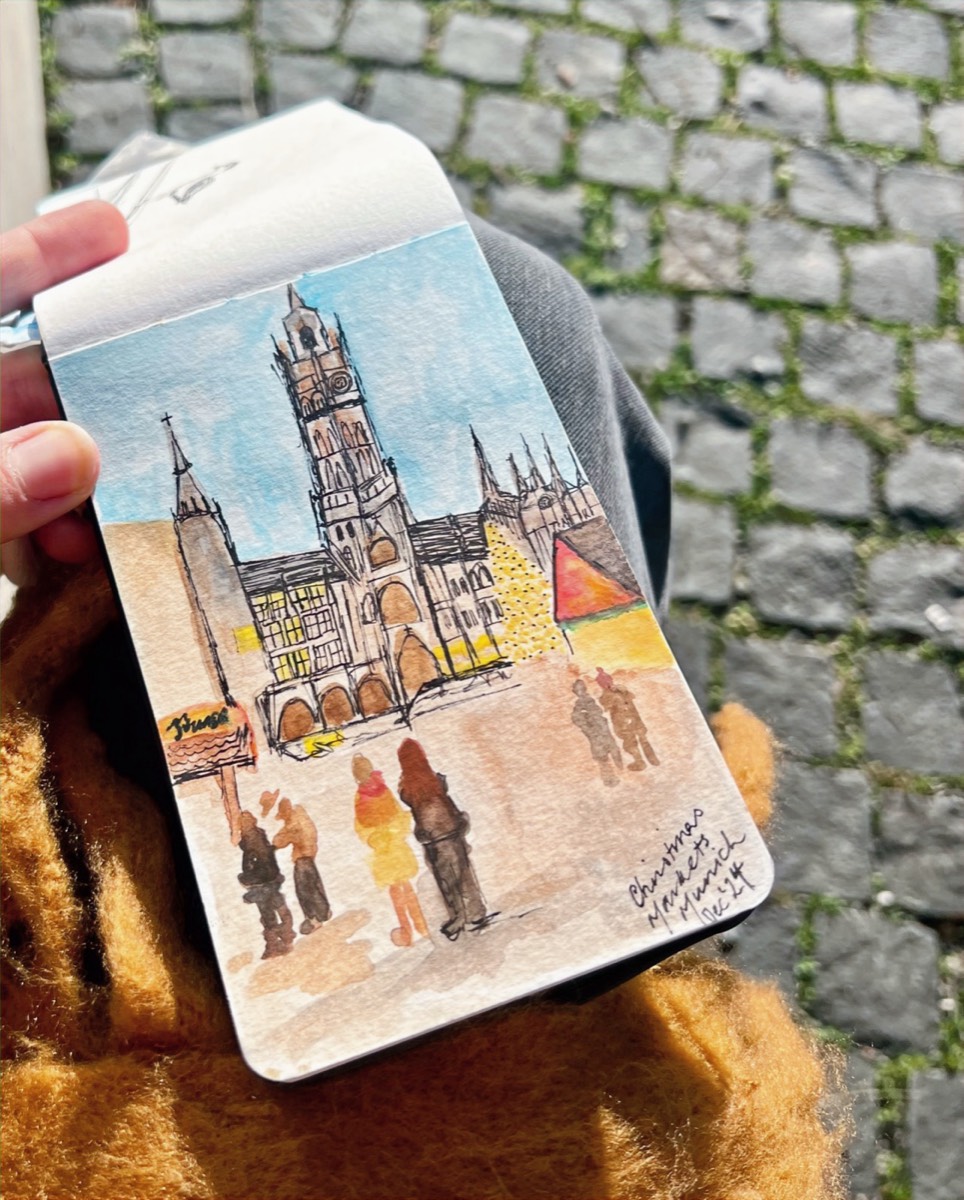 Lou Lou’s watercolour sketch of the Christmas markets in Munich, held over a cobbled street