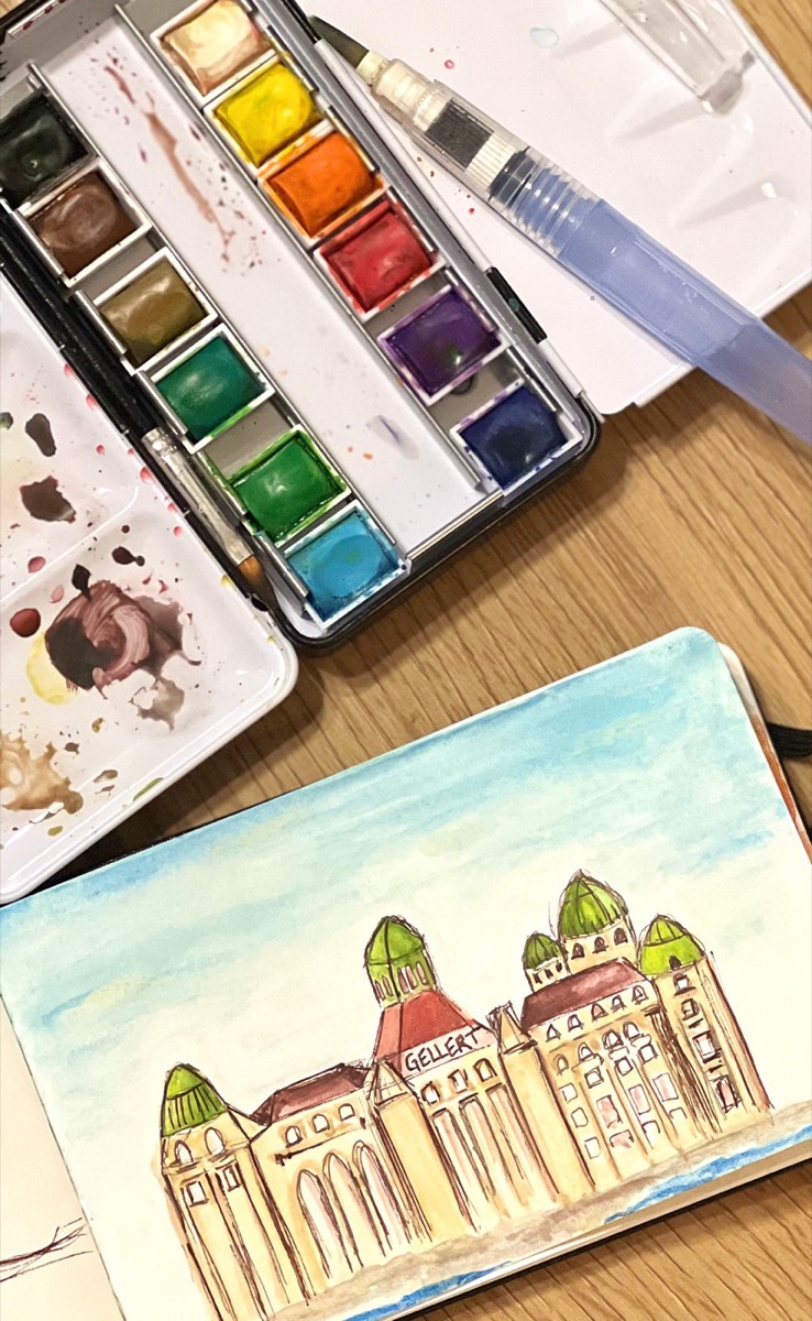 A watercolour palette beside a painting of a European building